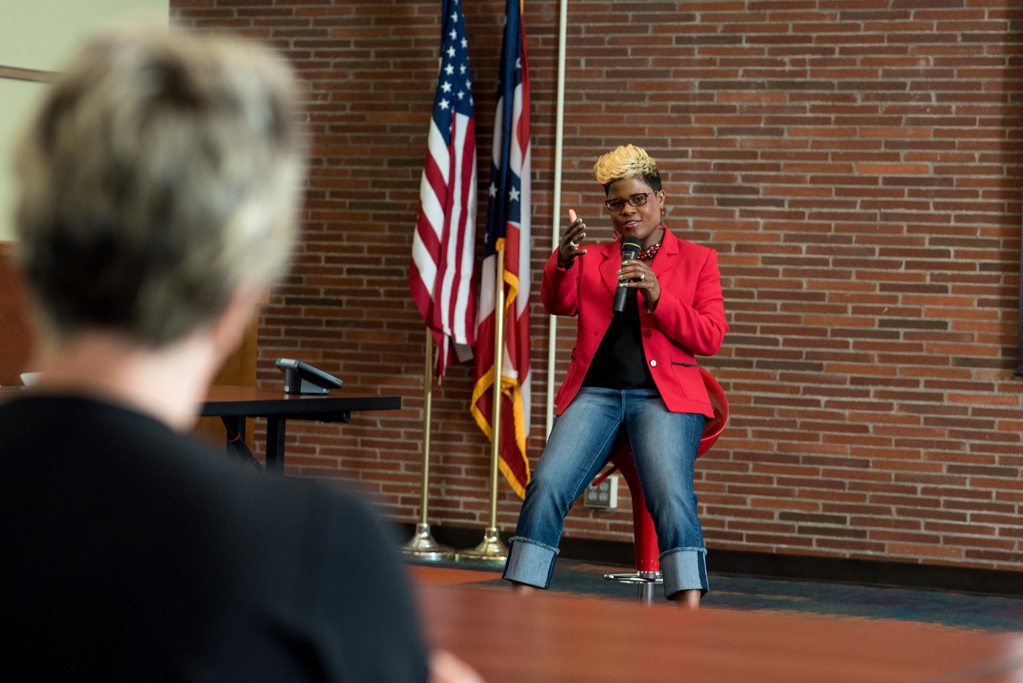 Tiffany Lewis | Speaking wearing Red Jacket | color photo
